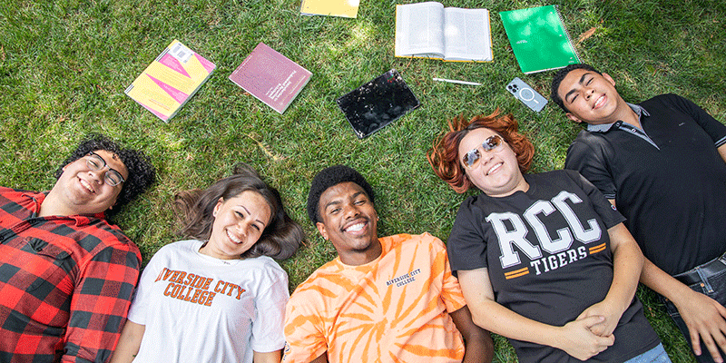 students laying on. the grass with books